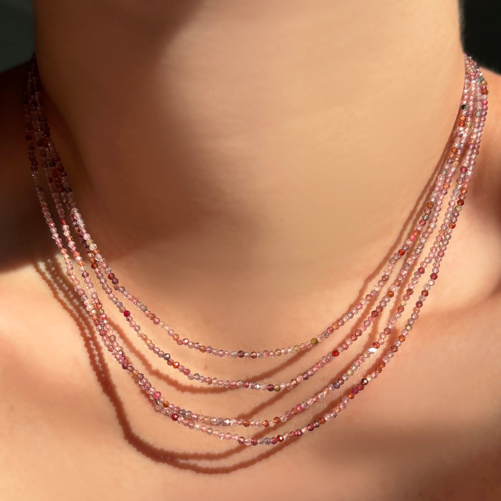 red pink faceted spinel slim gemstone necklaces on a model's neck.